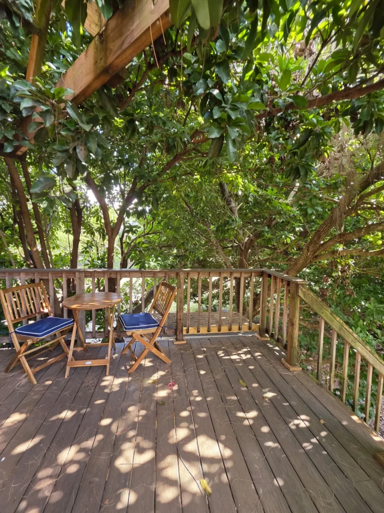 SunnyTops Treehouse outdoor deck with chairs and table, perfect for a relaxing treehouse getaway in Florida.