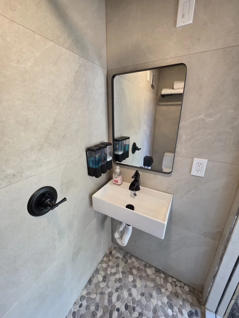 Modern treehouse bathroom with stone tile walls, floating sink, and decorative accessories for a relaxing treehouse getaway.