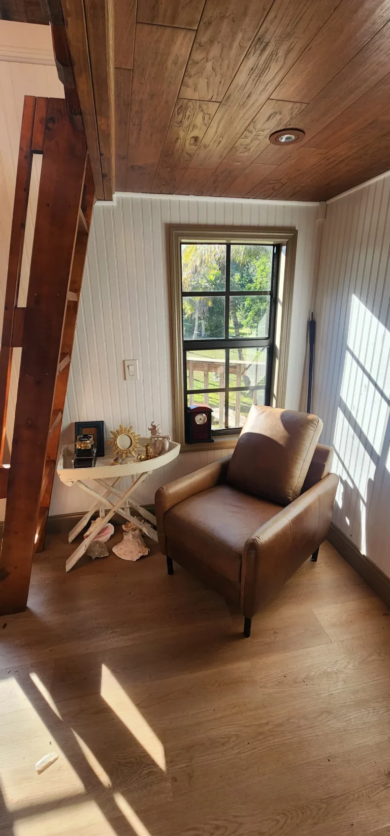 Cozy treehouse interior featuring leather sofa, wooden stairs, and natural light. Perfect for treehouse getaways in Florida.