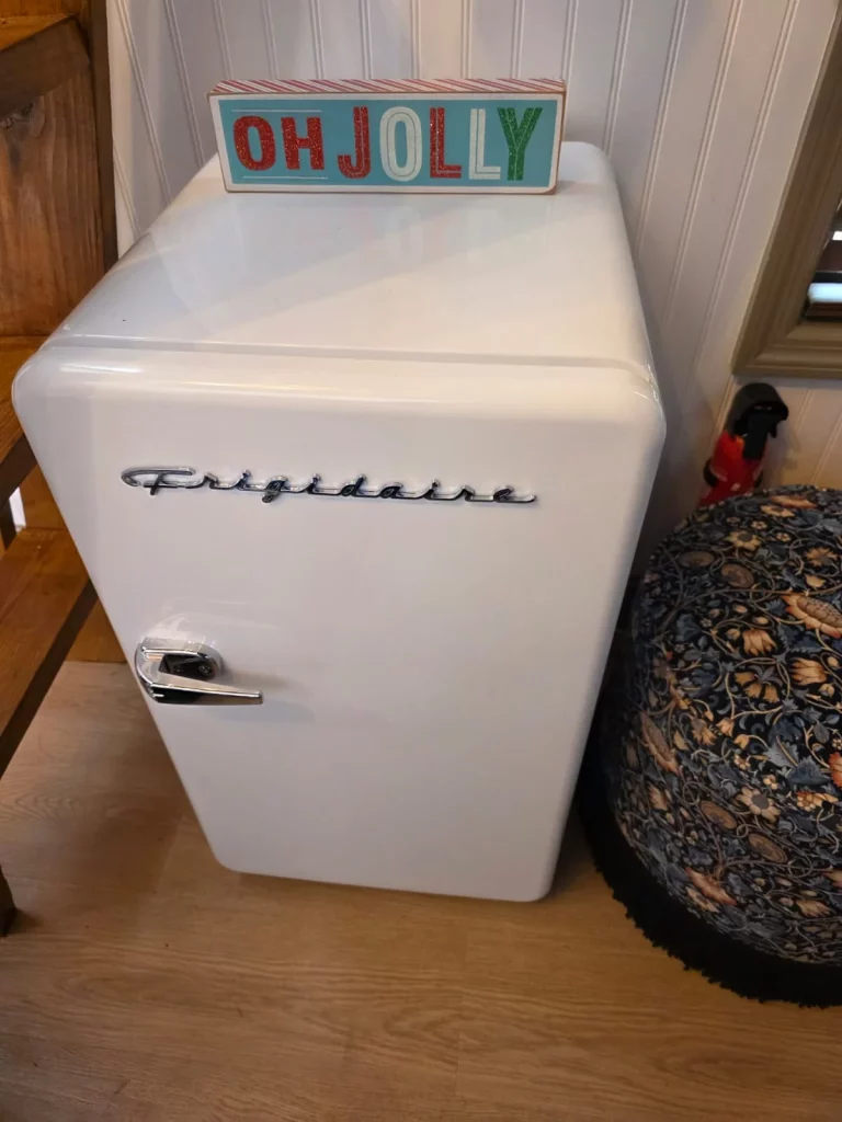 Cozy treehouse interior detail featuring a vintage Frigidaire mini-fridge and holiday decor, perfect for a treehouse getaway