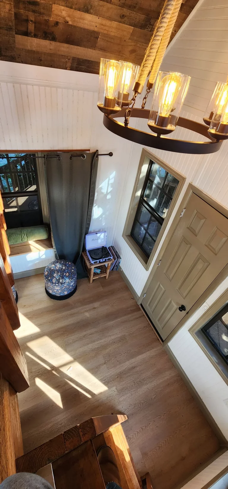 Interior of a treehouse rental, showing wooden walls and floors with cozy decor and sunlight for a relaxing getaway.